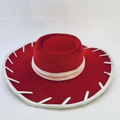 a red hat with white pins on the brim is sitting on a white surface