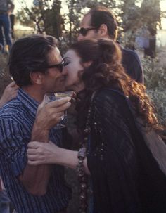 two people kissing each other while standing outside