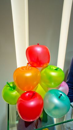 there are many different colored balloons on the glass table in front of eachother