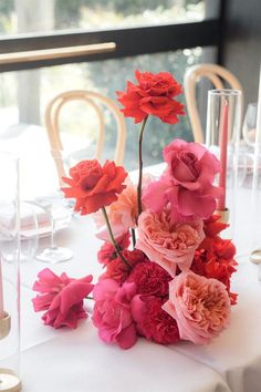 the flowers are arranged on the table near candles