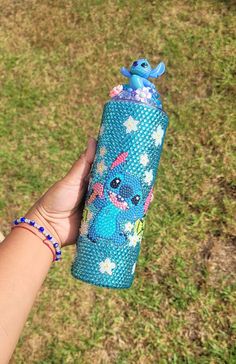 someone is holding a blue water bottle with an image of stitching on it in the grass