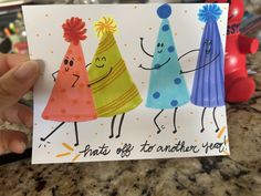 a hand holding up a card with three different colored hats on it and the words, that's off to another year