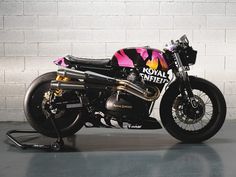 a black and pink motorcycle parked next to a brick wall