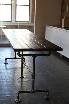 a long table in an empty room next to a window with bars on the legs