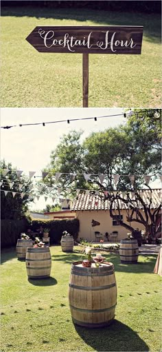 a wooden sign sitting on the side of a lush green field next to barrels filled with flowers