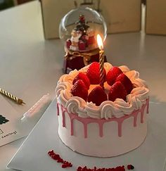 a birthday cake with white frosting and strawberries on top, sitting on a table