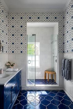 a bathroom with blue and white tiles on the floor, shower stall and sink area