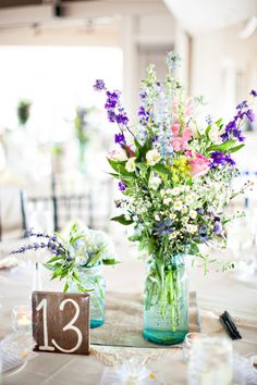 several vases filled with flowers sitting on top of a table covered in white cloth