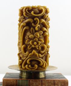 an intricately carved candle sits on top of two books