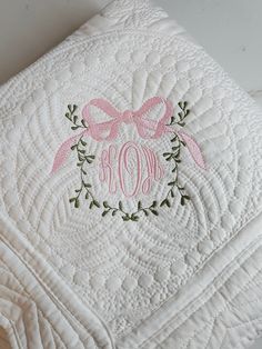 the monogrammed blanket has a pink bow on it and is embroidered with an initial