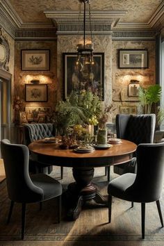 a dining room table with chairs around it and pictures on the wall behind it, along with potted plants