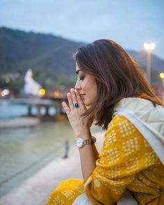 a woman sitting on the ground with her hands clasped to her face