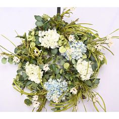 a bunch of white and blue flowers are arranged in a circular arrangement on a wall