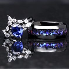 two wedding rings with blue and white diamonds on black reflective surface next to each other