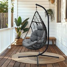 a hanging chair on a porch next to a potted plant