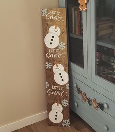 a wooden sign that says let it snow and two snowmen are on the front