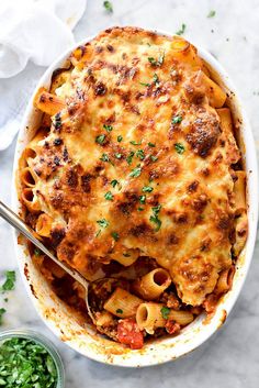 a casserole dish filled with pasta and meat, garnished with parsley