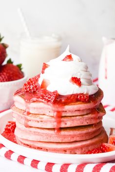 a stack of pancakes topped with whipped cream and strawberries