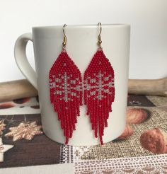 a pair of red beaded earrings sitting on top of a cup