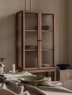 a wooden cabinet sitting next to a table with plates and cups on top of it