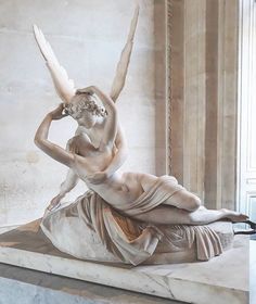 a statue of a woman laying on top of a white marble slab with an angel above her head