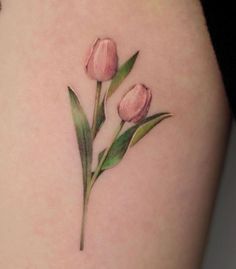 a close up of a person's thigh with tattoos on it and two pink tulips