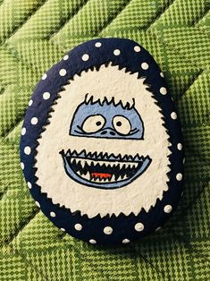 a close up of a button on a green surface with polka dotty dots and an evil face