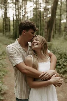 a young man and woman embracing each other in the woods