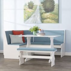 a white table with two benches and a blue bench seat in front of a painting on the wall