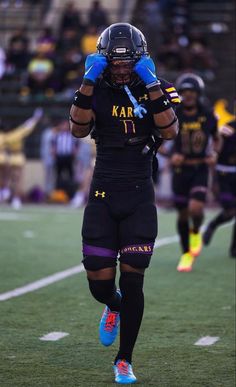 a football player is walking on the field with his hands behind his head while wearing blue gloves