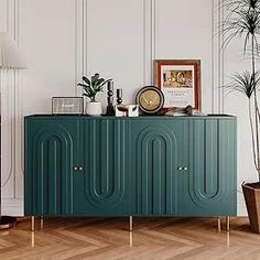 a living room with a large green cabinet and potted plants on the sideboard