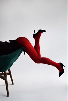 a woman in red stockings and black heels laying on a chair with her legs spread out