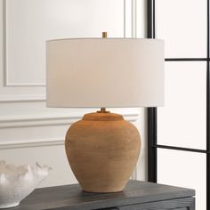 a table lamp sitting on top of a dresser next to a vase and seashell