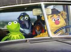 the muppets are driving in an old car