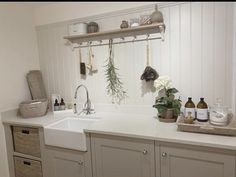 a kitchen with white cabinets and hanging herbs on the wall above the sink is an assortment of soaps, toothbrushes, and other items