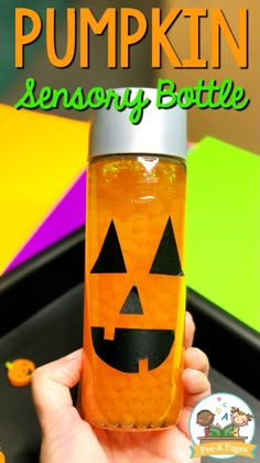 a hand holding up a bottle filled with orange liquid and jack - o'- lantern faces