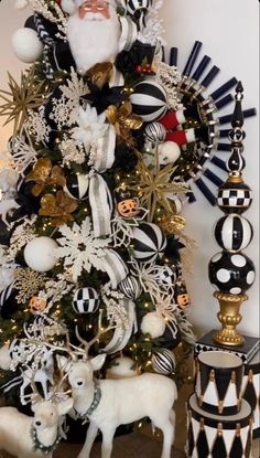 a christmas tree decorated with black and white ornaments, gold accents and a santa clause