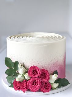 a white and pink cake with roses on top