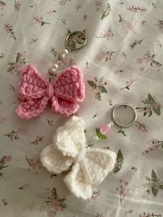 two crocheted butterfly keychains are laying on a flowered sheet with a pair of scissors