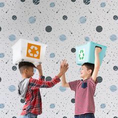 two young boys are holding up boxes with recyclables on their heads