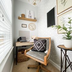 a room with a desk, chair and clock on the wall next to a window