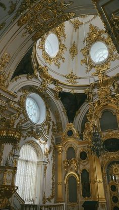 an ornate gold and white room with three round windows