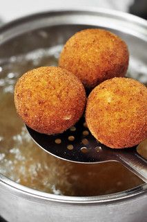 three fried food items in a saucepan with a ladle full of boiling water