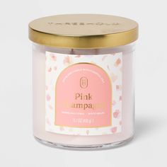 a pink candle with gold lid sitting on a white surface