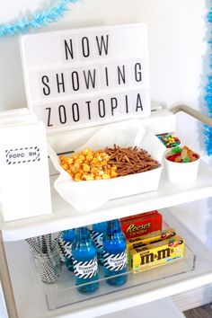 a white shelf topped with lots of food next to blue streamers and paper pom poms