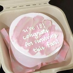 a cake in a container with writing on the top and pink ribbon around it's edges