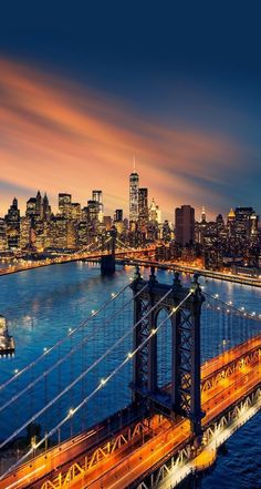 an aerial view of the brooklyn bridge at night with city lights and skyscrapers in the background