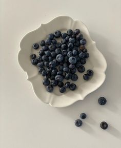 a white bowl filled with blueberries on top of a table