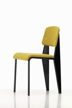 a yellow and black chair sitting on top of a white floor next to a wall