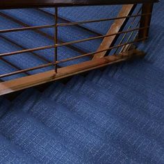 an open suitcase sitting on top of a blue carpeted floor next to a stair case